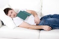 Tired young man sleeping on couch with book on lap Royalty Free Stock Photo