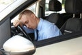 Tired young man sleeping on steering wheel in car Royalty Free Stock Photo