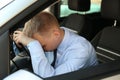 Tired young man sleeping on steering wheel in car Royalty Free Stock Photo