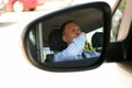 Tired man yawning in his auto, view through car side mirror