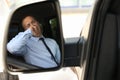 Tired man yawning in his auto, view through car side mirror