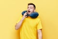 Tired young man yawning on yellow background