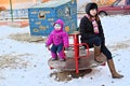 Tired young mother and child on a swing in winter