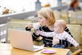 Tired young mother holding 6-month daughter and drinking coffee Royalty Free Stock Photo