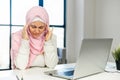 A tired young muslim woman wearing hijab using a laptop Royalty Free Stock Photo