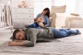 Tired young parents with their baby sleeping on floor in children`s room Royalty Free Stock Photo