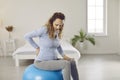 Tired young pregnant woman with back pain doing pain relief exercises on a fit ball Royalty Free Stock Photo