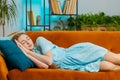 Tired young redhead woman lying down in bed taking a rest at home, napping, falling asleep on sofa Royalty Free Stock Photo