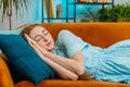 Tired young redhead woman lying down in bed taking a rest at home, napping, falling asleep on sofa Royalty Free Stock Photo