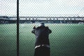 Tired young sporty man leaned and holding on to the rabitz fence