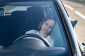 Tired young woman asleep on pillow on steering wheel, resting after long hours driving a car. Fatigue Royalty Free Stock Photo