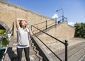 Tired young woman drinking water on stairs