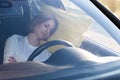 Tired young woman driver asleep on pillow inside her car, resting after long hours driving. Fatigue Royalty Free Stock Photo