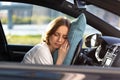 Tired young woman driver asleep on pillow on steering wheel, resting after long hours driving a car. Fatigue Royalty Free Stock Photo