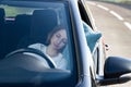 Tired young woman driver asleep on pillow on steering wheel, resting after long hours driving a car. Fatigue Royalty Free Stock Photo