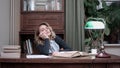 Tired young woman falling asleep over a book while sitting at the table Royalty Free Stock Photo