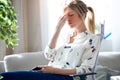 Tired young woman with headache holding her mobile phone at the office