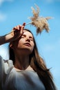 Tired young woman holding fluffs at her forehead, low angle