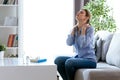 Tired young woman with neck pain sitting on the couch at home.