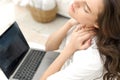 Tired young woman with neck pain working in laptop at home office. Tired young woman touching her stiff neck, feeling Royalty Free Stock Photo
