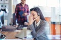 Tired young woman is sitting at the table at work in a call center. Royalty Free Stock Photo