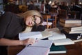 Tired young woman student of the University. Preparing exam and learning lessons in public library. Royalty Free Stock Photo