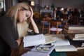 Tired young woman student of the University. Preparing exam and learning lessons in public library. Royalty Free Stock Photo