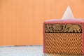 Tissue box Thai pattern placed on a glass table on the balcony of the room, orange wall background Royalty Free Stock Photo