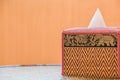 Tissue box Thai pattern placed on a glass table on the balcony of the room, orange wall background Royalty Free Stock Photo