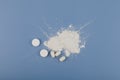 Titanium dioxide, TiO2. Food additive E171. White chemical powder, chewing gum and pills on blue. Titanium dioxide used as pigment