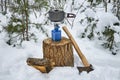 Titanium pot on portable camping stove stands on stump, firewood and axe on snow in winter forest near stump Royalty Free Stock Photo