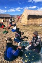 TITICACA LAKE, PERU Uros indigenous women in traditional clothing busy with their handicrafts on the floating islands