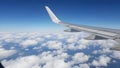 Title: Airplane wing with blue sky and fluffy white clouds in the background during flight Royalty Free Stock Photo