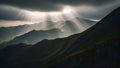 Title: Sun rays breaking through clouds over a misty mountain landscape with rolling hills and Royalty Free Stock Photo