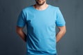 Young man in blank blue t-shirt on grey background. Mock up Ai generative Royalty Free Stock Photo
