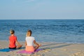 Young women practicing yoga on the beach at sunset. Girls meditating, sitting in lotus pose Royalty Free Stock Photo