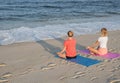 Young women practicing yoga on the beach at sunset. Girls meditating, sitting in lotus pose Royalty Free Stock Photo