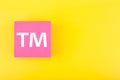 TM trademark sign on pink figure on yellow background with copy space