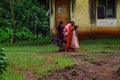 30 to 40 aged Indian women wearing saree standing outside of the house and talking to each other. house and trees on background.