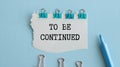 To Be Continued text message and alarm clock on wooden background Royalty Free Stock Photo