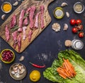 To cut thin slices beef with garlic on a cutting board with a knife for meat, butter and salt, lettuce wooden rustic background