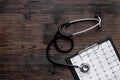 To diagnose heart disease. Cardiogram, stethoscope on dark wooden background top view copyspace