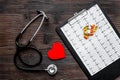 To diagnose heart disease. Heart sign, cardiogram, stethoscope on dark wooden background top view
