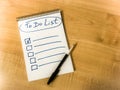 to do list checklist hand written on notepad paper lay on wooden table. pen lay on notepad Royalty Free Stock Photo