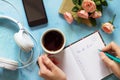 To do list concept. A smartphone, headphones and an open notebook next to a cup of coffee on a blue slate or concrete background. Royalty Free Stock Photo