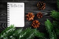 To do list for winter shopping at notebook near spruce branch and pinecones on grey wooden background top view Royalty Free Stock Photo