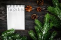 To do list for winter shopping at notebook near spruce branch and pinecones on grey wooden background top view Royalty Free Stock Photo