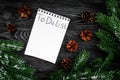 To do list for winter shopping at notebook near spruce branch and pinecones on grey wooden background top view Royalty Free Stock Photo