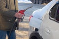 To fill up the car with gasoline at the gas station, a man pours gasoline into the tank of a white car in winter