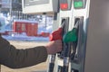 To fill up the car with gasoline at the gas station, a man pours gasoline into the tank of a white car in winter